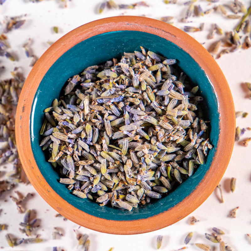 Lavender Flower herb in blue clay bowl with white background and herb surrounding.