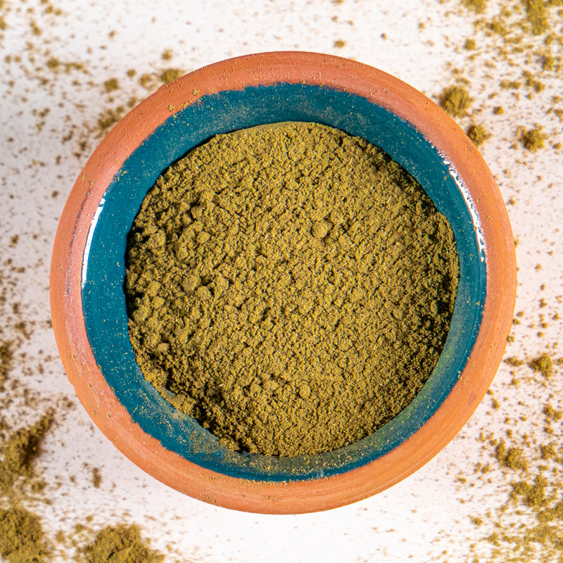 Lemon Balm powder herb in blue clay bowl with white background and herb surrounding.