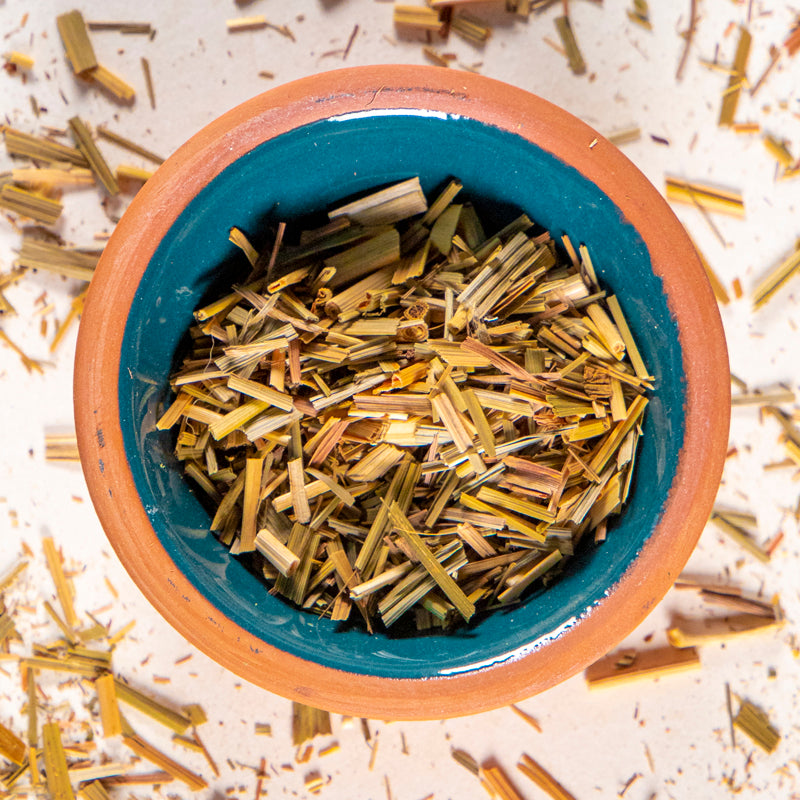 Lemongrass herb in blue clay bowl with white background and herb surrounding.