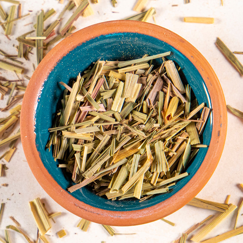 Lemongrass herb in blue clay bowl with white background and herb surrounding.