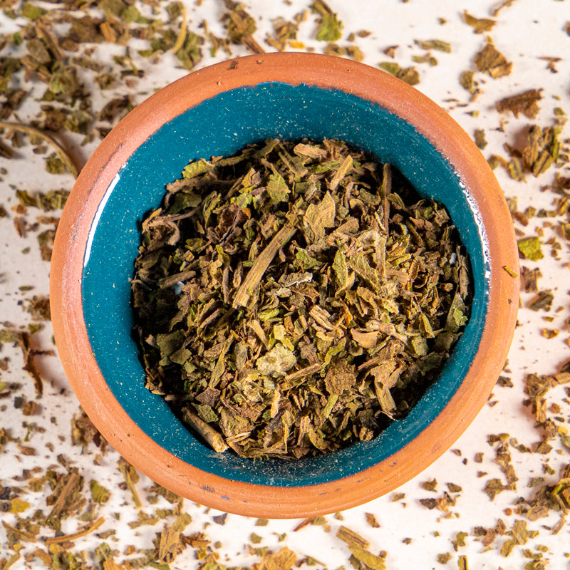 Lobelia herb in blue clay bowl with white background and herb surrounding.