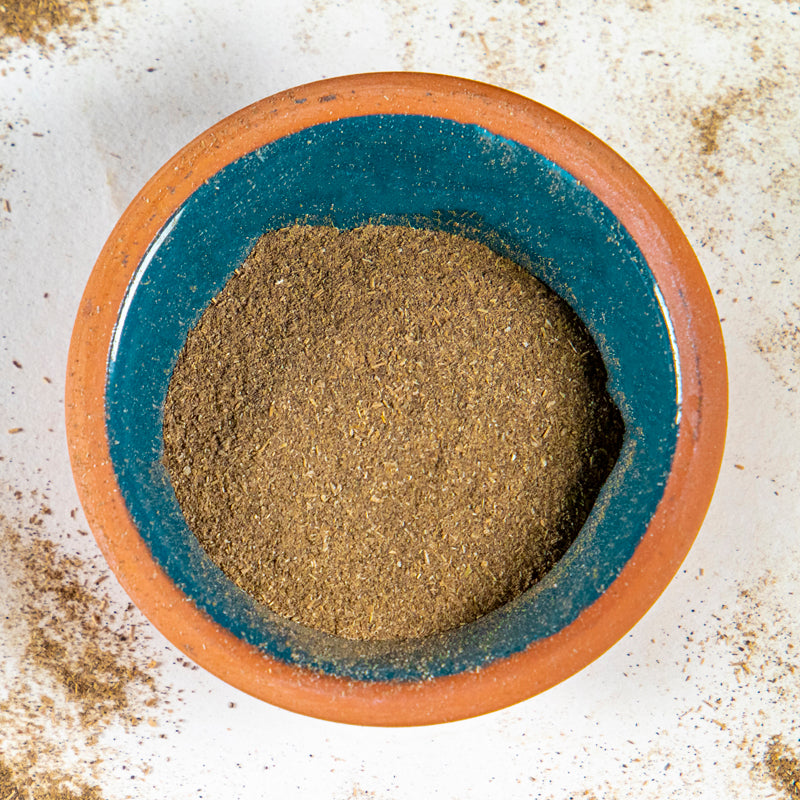 Milk Thistle Seed Powder herb in blue clay bowl with white background and herb surrounding.