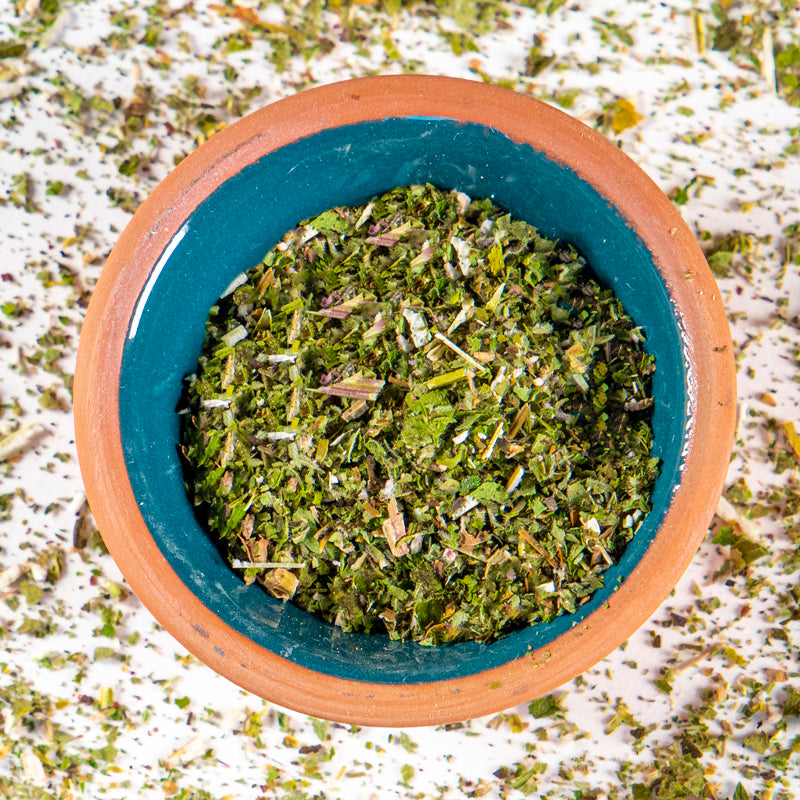 Motherwort herb in blue clay bowl with white background and herb surrounding.