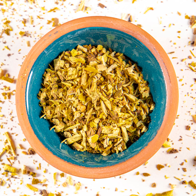 Oregon Grape Root herb in blue clay bowl with white background and herb surrounding.