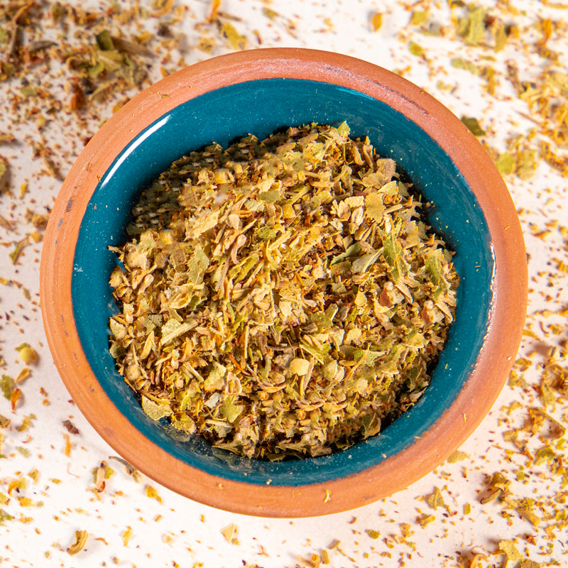 Linden Flowers and Leaves herb in blue clay bowl with white background and herb surrounding.